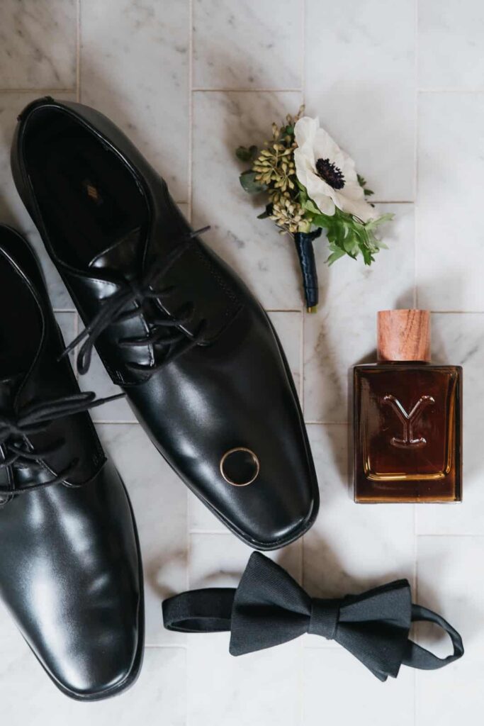 groom detail photo with shoes, boutonniere, ring, cologne and bowtie